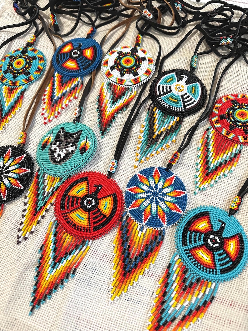 Op de afbeelding: Een verzameling van kralen Native American dreamcatchers met kleurrijke geometrische patronen en franjes. De dreamcatchers zijn gemaakt met turquoise, rode, gele, witte en zwarte kralen.