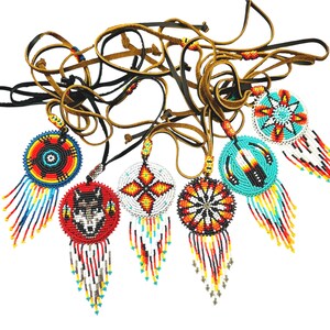 May include: A set of eight beaded Native American dreamcatchers with leather cords. The dreamcatchers feature various designs, including a wolf, a star, and a flower. The dreamcatchers are all different colours, including red, blue, yellow, and white.