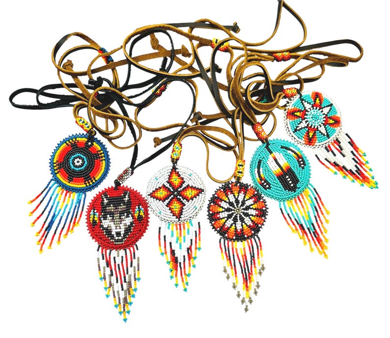 May include: A set of eight beaded Native American dreamcatchers with leather cords. The dreamcatchers feature various designs, including a wolf, a star, and a flower. The dreamcatchers are all different colours, including red, blue, yellow, and white.
