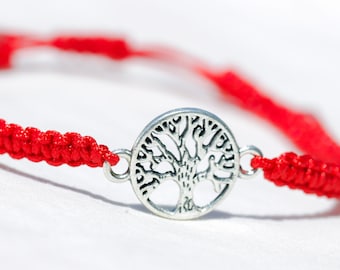 May include: A red string bracelet with a silver tree of life charm.