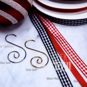 May include: Ornament hanger options: silver swirl, gold swirl, black plaid ribbon, red plaid ribbon, and red ribbon.