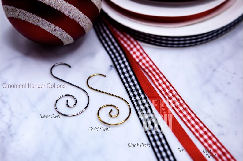 May include: Ornament hanger options: silver swirl, gold swirl, black plaid ribbon, red plaid ribbon, and red ribbon.
