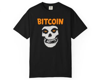 May include: Black t-shirt with the word "BITCOIN" in orange block letters above a white skull graphic with orange eyes. The shirt is a short-sleeved crew neck.
