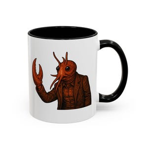 May include: A white ceramic mug with a black handle and the text "But First, Coffee" in a bold, black font. The mug is set against a blurred background, suggesting a cozy setting.