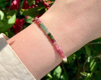 May include: A bracelet made of small, multi-colored gemstones. The bracelet is made of pink, green, and white gemstones.