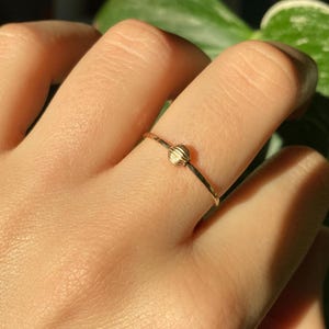 Peut inclure: Une délicate bague en or avec une perle ronde en or texturée au centre.