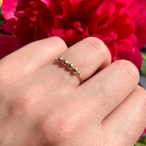 Può includere: Un anello d'oro con una fila di cinque piccole perle rotonde.