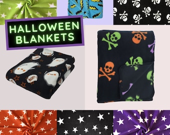 May include: A collection of Halloween-themed blankets in various patterns. Designs include white stars on green, black, orange, and purple backgrounds, along with skull and crossbones, ghosts, and lightning bolts. The text "HALLOWEEN BLANKETS" is displayed.