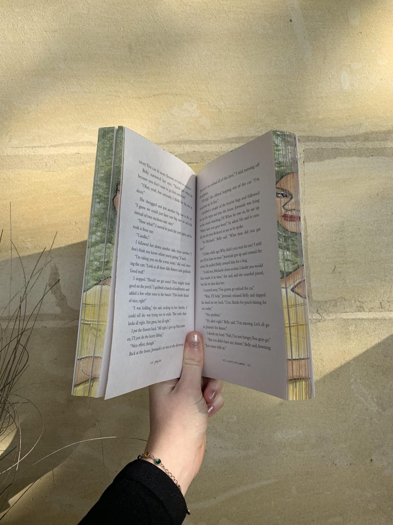 Pode incluir: Um livro aberto com texto impresso e ilustra&ccedil;&otilde;es, segurado por uma m&atilde;o. As p&aacute;ginas do livro s&atilde;o brancas e a capa apresenta um design verde e branco. As ilustra&ccedil;&otilde;es parecem ser de uma pessoa. O livro est&aacute; aberto, revelando o texto.