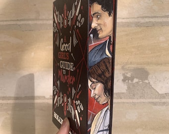 May include: A book titled "A Good Girl's Guide to Murder" by Holly Jackson. The book's cover is black with red text and illustrations of knives, footprints, and other objects. The book's spine features portraits of two people.