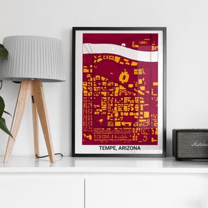 May include: A framed print of a city map in maroon and gold colors. The map is titled "Tempe, Arizona". The print is displayed on a white shelf with a lamp and a speaker.