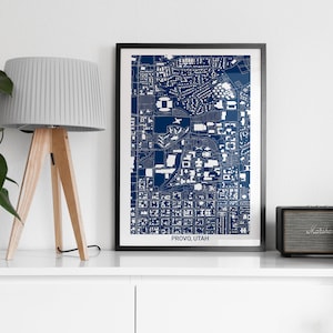 May include: A framed print of a blue and white map of Provo, Utah. The map shows the city's streets and buildings. The frame is black and the print is on white paper.