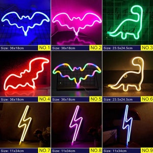 May include: Collection of neon LED lights in various shapes: a bat (36x18cm), a dinosaur (23.5x24.5cm), and a lightning bolt (11x34cm). Each light emits a vibrant color, including blue, pink, green, and yellow.