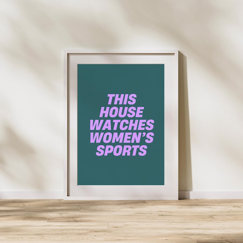 Pode incluir: Uma impress&atilde;o emoldurada com fundo azul-esverdeado e moldura branca. O texto "THIS HOUSE WATCHES WOMEN'S SPORTS" est&aacute; escrito em roxo.