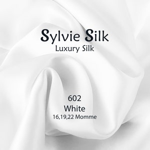May include: White silk fabric with the text "Sylvie Silk Luxury Silk 602 White 16,19,22 Momme" printed on it.