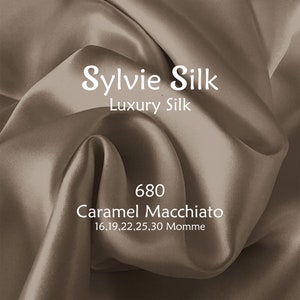 May include: A close-up of a flowing fabric in a caramel color. The text "Sylvie Silk, Luxury Silk" is displayed in white. Below, the text reads "680 Caramel Macchiato 16,19,22,25,30 Momme".