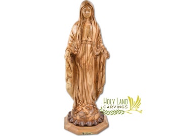 May include: A hand-carved wooden statue of the Virgin Mary, standing on a wooden base. The statue is made of olive wood and has a natural wood finish. The statue is about 12 inches tall. The base is octagonal and has a small inscription that reads "Holy Land Carvings".