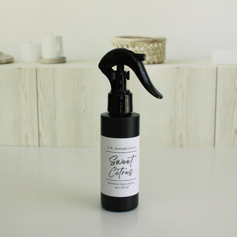 May include: A black room and linen spray bottle with a black trigger. The label reads "Sweet Citrus" and "Room & Linen Spray 4oz 118 ml". The bottle is on a white surface.