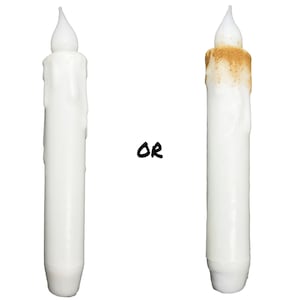 May include: Two white LED candles with a drippy wax design. The candle on the left is clean, while the candle on the right has a brown stain on the top.