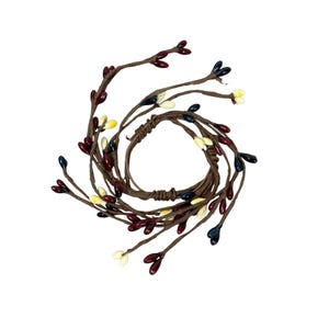 May include: A decorative berry garland in a circular shape. The garland features brown stems with small, colorful berries in shades of burgundy, cream, yellow, and navy blue. The berries are evenly spaced along the stems.