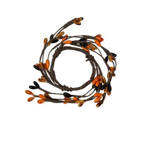 May include: A decorative ring made of brown twigs, adorned with orange, black, and amber-colored bead-like accents. The ring is designed in a circular shape, perfect for seasonal or holiday decor.