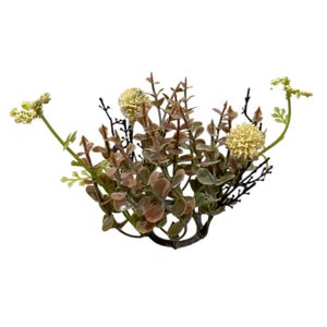 May include: Artificial plant arrangement featuring a mix of textures and colors. The arrangement includes small, rounded, brown and green leaves, delicate yellow flowers, and dark, twig-like stems. The plant is set against a white background.