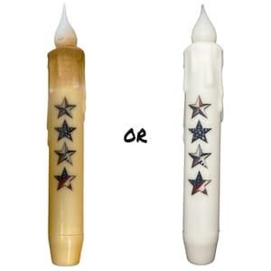 May include: Two LED flameless candles with a dripping wax design. Both candles have a white tip and are decorated with four red, white, and blue stars. The candle on the left is a beige color, and the candle on the right is white. "OR" is written in black text between the candles.