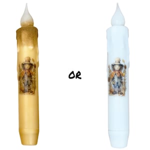 May include: Two decorative candles with a scarecrow design. The candle on the left is a light brown color and the candle on the right is white.