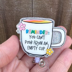 May include: A white ceramic mug with a black handle and the text "But First, Coffee" in a bold, black font. The mug is set against a blurred background, highlighting its clean design.