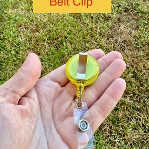 May include: A yellow belt clip with a silver metal clip and a clear plastic strap. The text "Belt Clip" is displayed on a yellow rectangle above the clip.