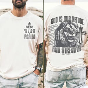 May include: Cream-colored t-shirt with a cross and the text "46:1-3 PSALM" on the front. The back features a lion graphic, a cross, and the words "GOD IS OUR REFUGE AND STRENGTH" with the scripture reference Psalm 46:1-3.