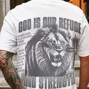 May include: White t-shirt with a large graphic of a roaring lion and the text "GOD IS OUR REFUGE AND STRENGTH" in gray. The shirt also features the Bible verse Psalm 46:1-3.