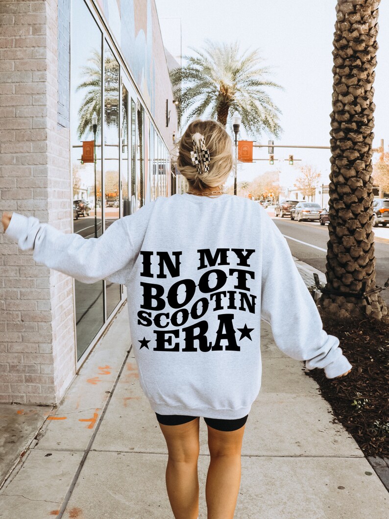 May include: A gray sweatshirt with the text "IN MY BOOT SCOOTIN ERA" printed in black on the back.
