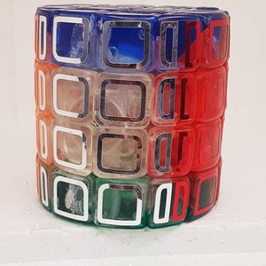 May include: A multi-colored, clear plastic puzzle with a square design. The puzzle is made up of small squares that are connected together. The squares are in different colors, including red, blue, green, and white.