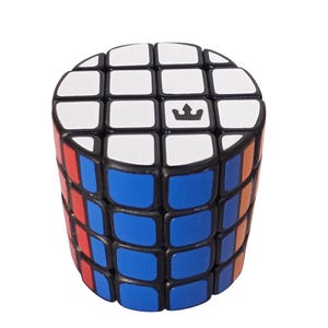 Op de afbeelding: Een cilindrisch puzzelspeelgoed met een kroonsymbool bovenop. Het speelgoed heeft een combinatie van rode, blauwe, oranje, witte en zwarte vierkanten. De puzzel is ontworpen om te worden gedraaid en gekeerd om op te lossen.