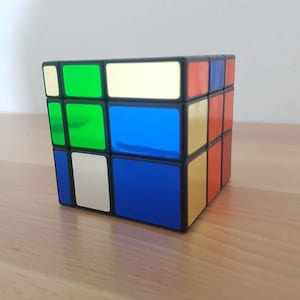 Puede incluir: Un cubo de Rubik negro con cuadrados verdes, azules, amarillos y rojos en los lados visibles.