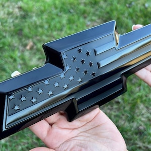 May include: Black Chevrolet emblem with an American flag design. The flag is embossed and has a glossy finish.