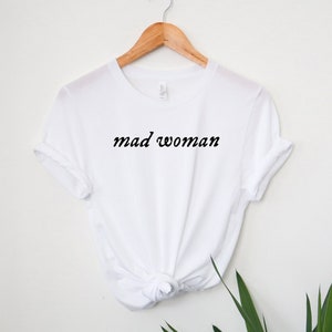 May include: White t-shirt with the text "mad woman" in black cursive lettering.