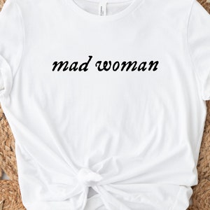 May include: White t-shirt with the text "mad woman" in black cursive lettering.
