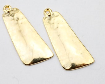 May include: Two gold-toned metal pendant charms shaped like a rectangle with rounded corners. The charms have a hammered texture and a hole at the top for attaching to a chain or cord.