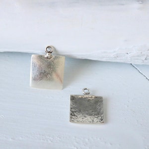 May include: Two silver square pendant charms, one smooth and one with a hammered texture.