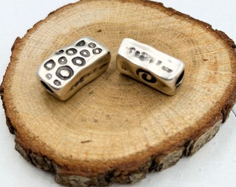 May include: Two silver metal beads with different designs. One bead has a circular pattern and the other has a swirl pattern.