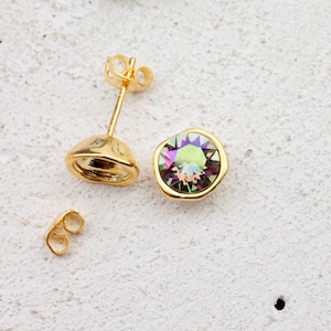May include: A pair of gold earrings with a round iridescent gemstone. The earrings have a post and butterfly back.