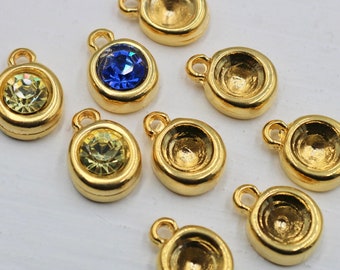 May include: Assortment of gold-tone metal charms with various colored rhinestones. The charms feature a round shape with a small loop at the top for attaching to jewelry or other crafts.
