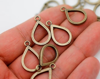 Könnte beinhalten: Nahaufnahme von mehreren antiken, goldfarbenen, tropfenförmigen Ohrringrohlingen aus Metall mit einer Öse oben. Die Ohrringrohlinge sind auf einer Hand angeordnet.