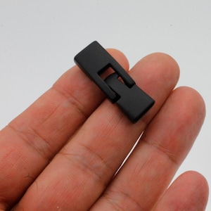May include: Black metal watch band connector clasp.