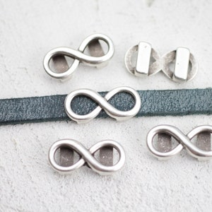 May include: Five silver infinity symbol charms, some with a leather strap, for jewelry making.