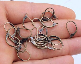 May include: A collection of antique bronze-colored leverback earring findings. The findings are in various stages of being open and closed, with a small loop at the top for attaching to the earring design. The leverback style provides a secure closure.