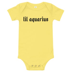 May include: Yellow baby onesie with black text that reads "lil aquarius".