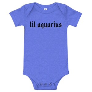 May include: A blue baby onesie with short sleeves and black text that reads "lil aquarius".